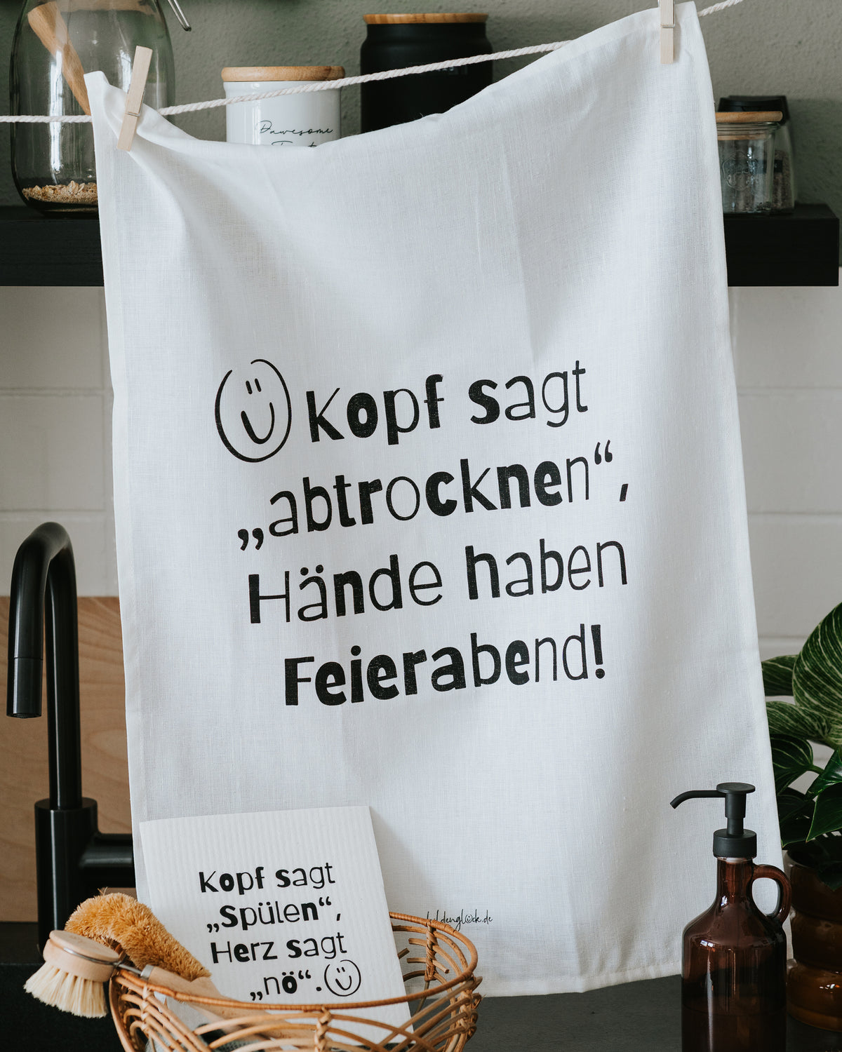 Geschirrtuch „Kopf sagt ‚abtrocknen‘, Hände haben Feierabend!“ am Schrankgriff.