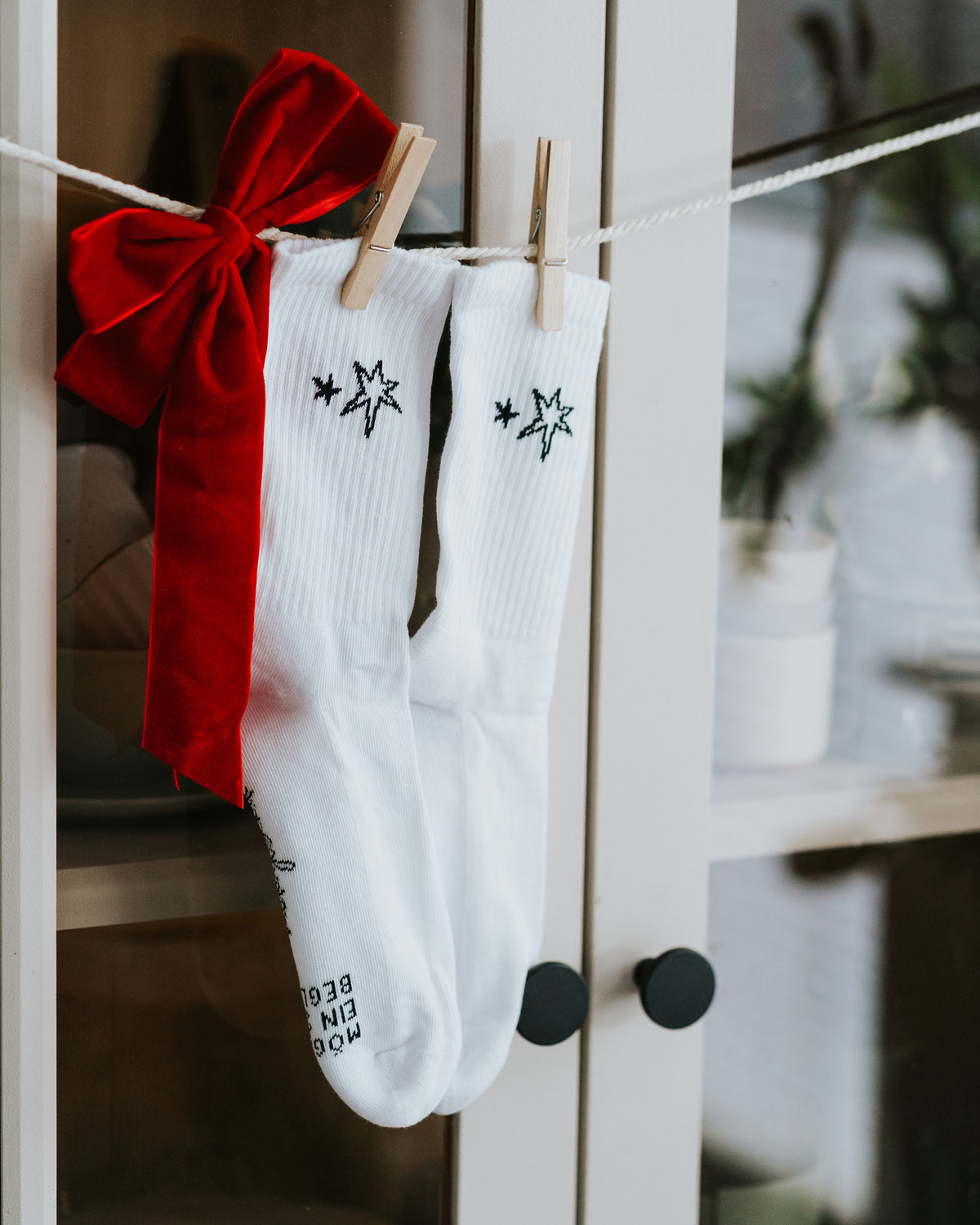 Socken an weißer Leiter, rote Samtschleife daneben.