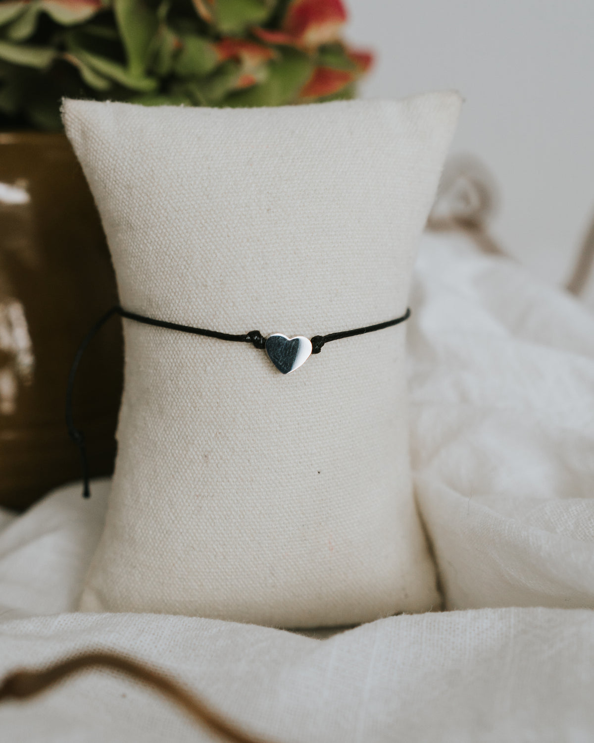 Baumwoll-Armband mit silbernem Herz am Schmuckständer.