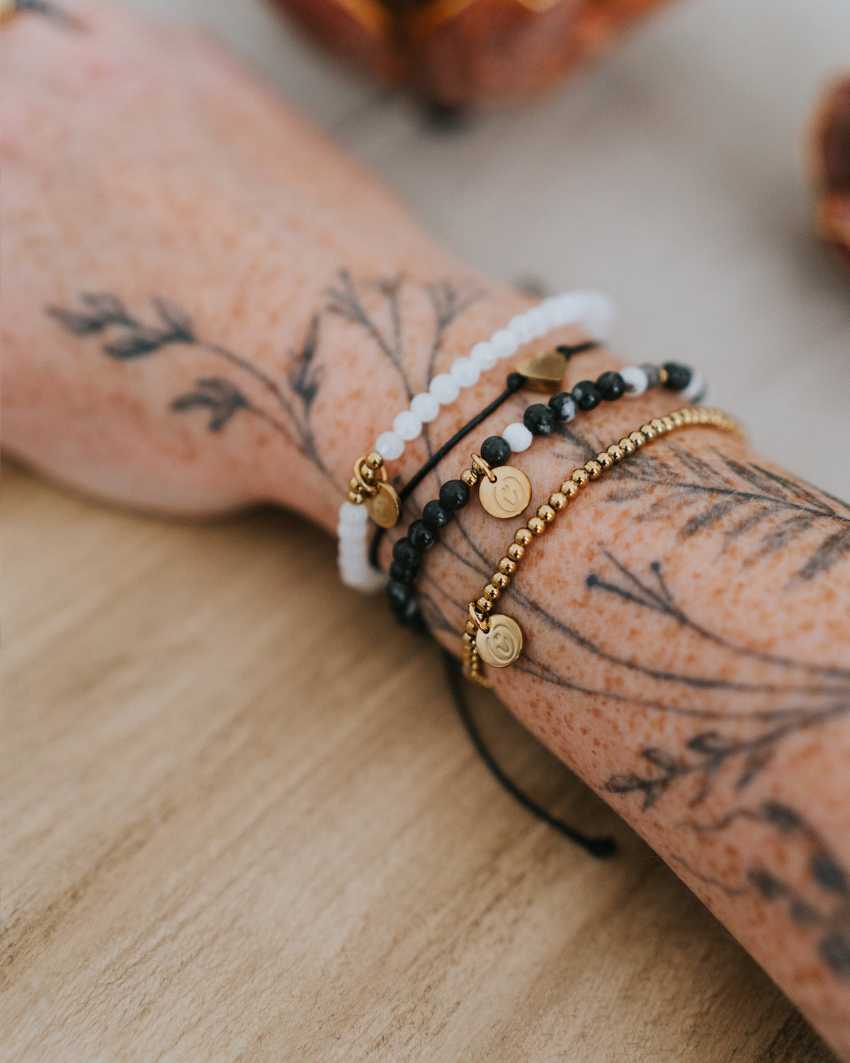 Edelstahl-Armband in Gold am Handgelenk, mit weiteren Armbändern kombiniert.