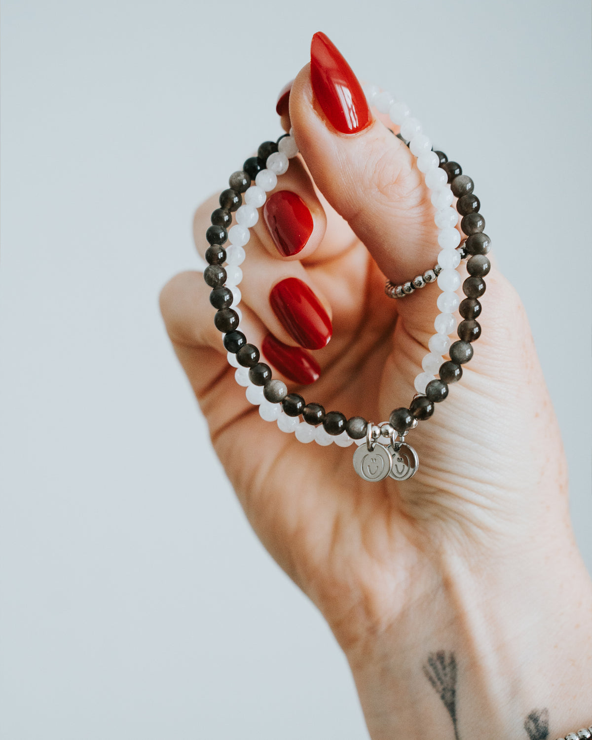 Hand hält Obsidian-Armband in Silber – Anhänger sichtbar.