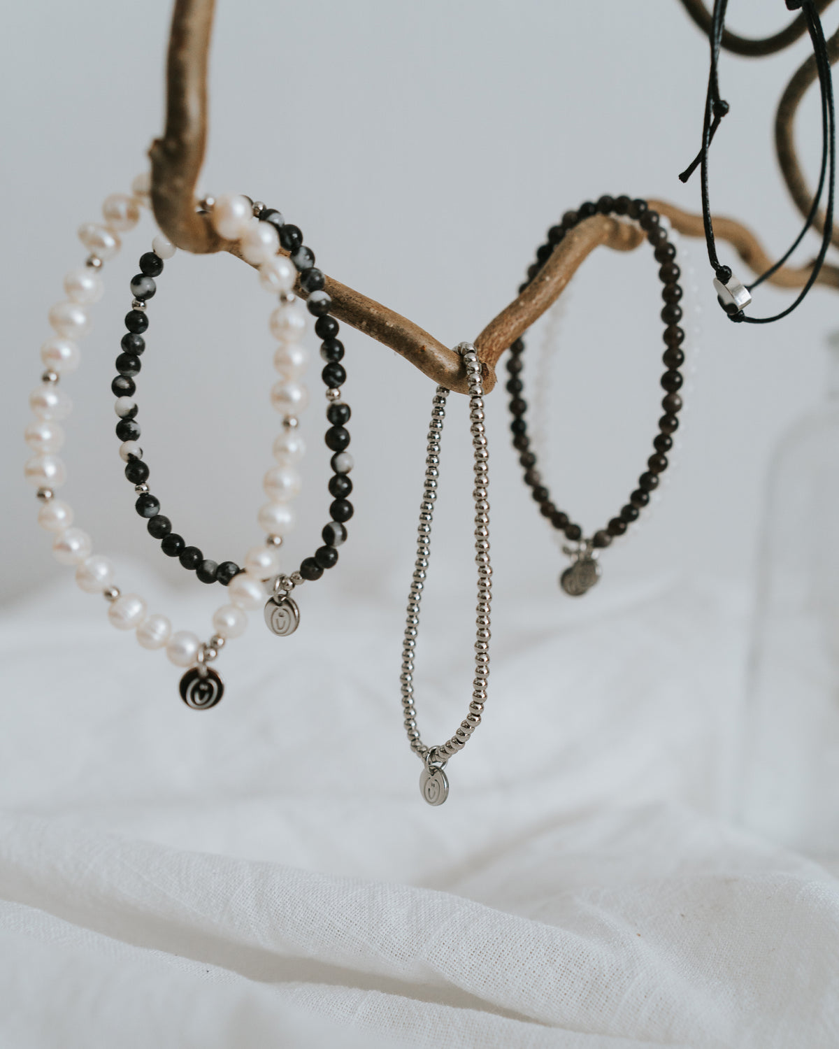 Süßwasserperlen-Armband in Silber flach neben feiner Kette.