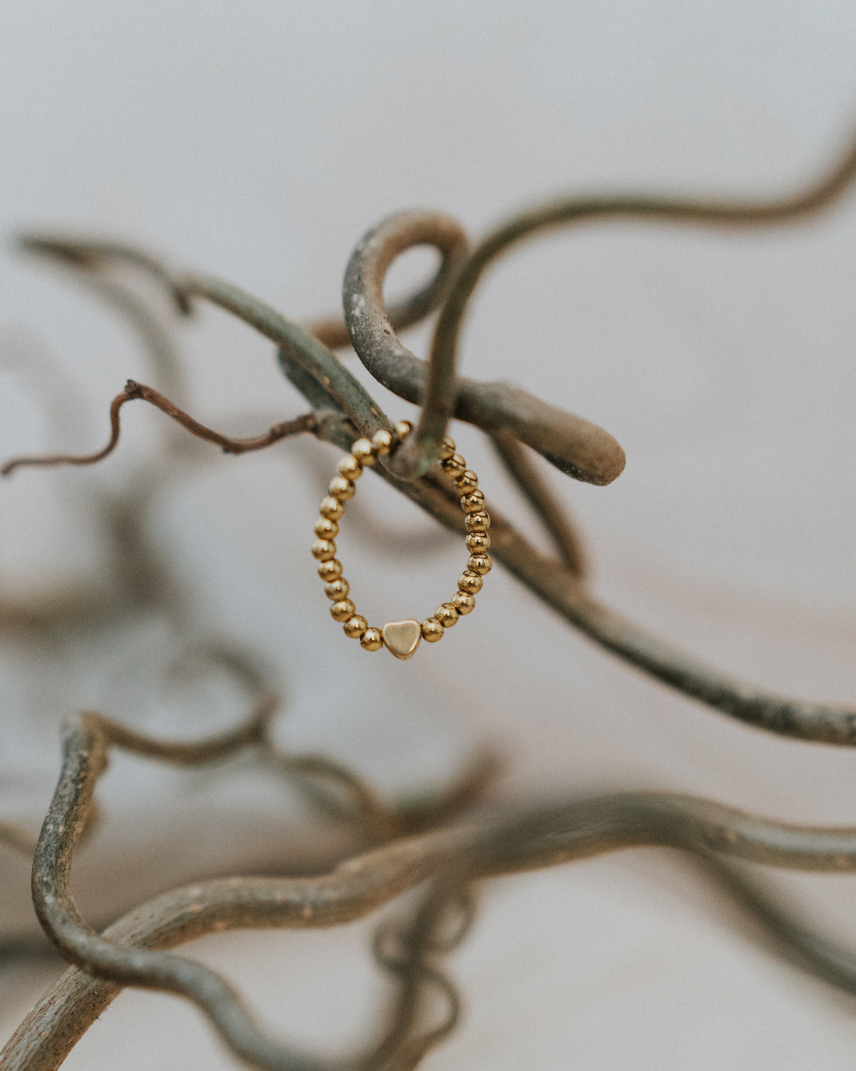 Edelstahl-Ring in Gold an Zweigen – goldfarbene Kugeln mit goldenem Herz.