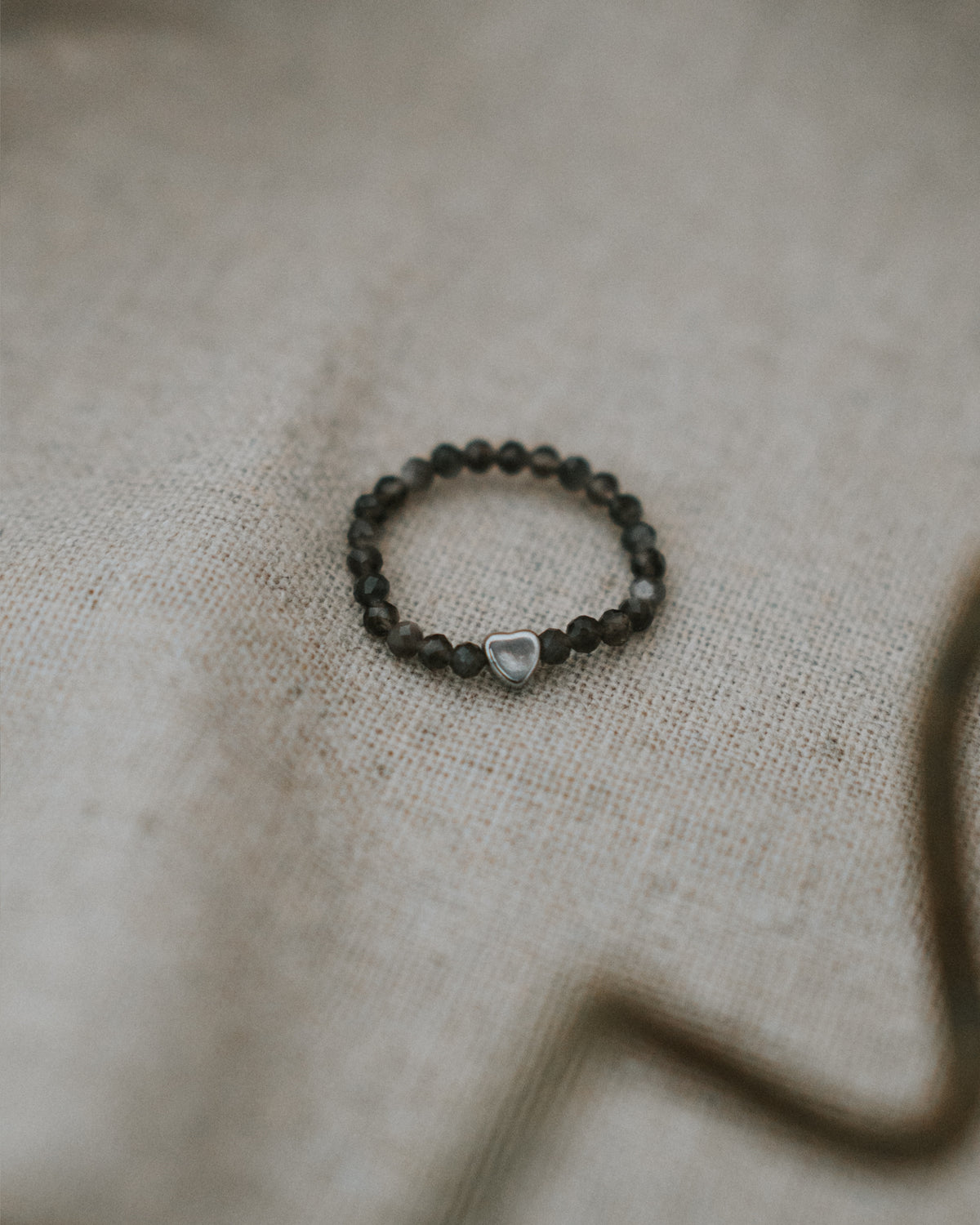 Obsidian-Ring flach auf Leinen, Nahaufnahme.