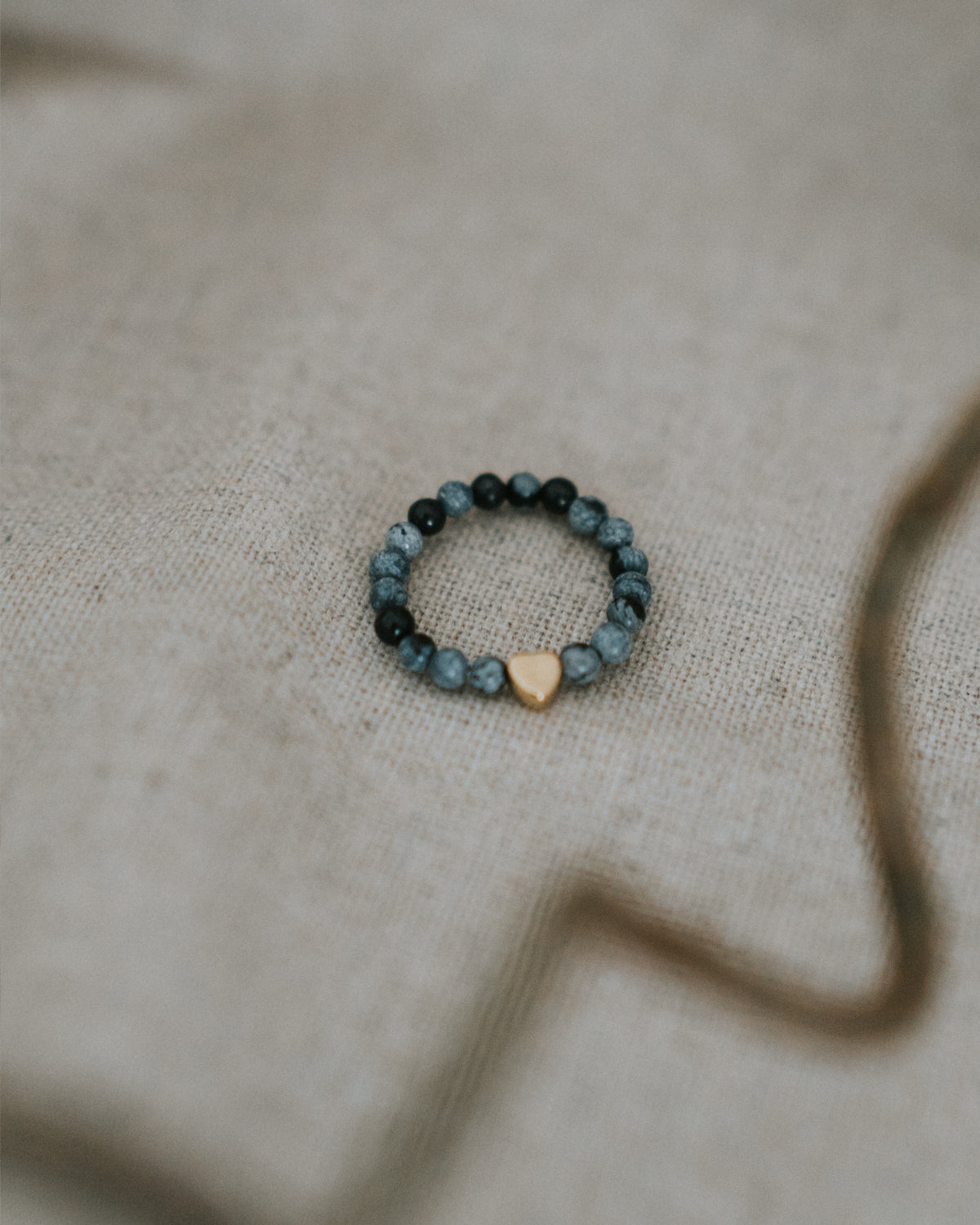Zebra-Jaspis-Ring flach auf Leinen – Perlen mit goldenem Herz.