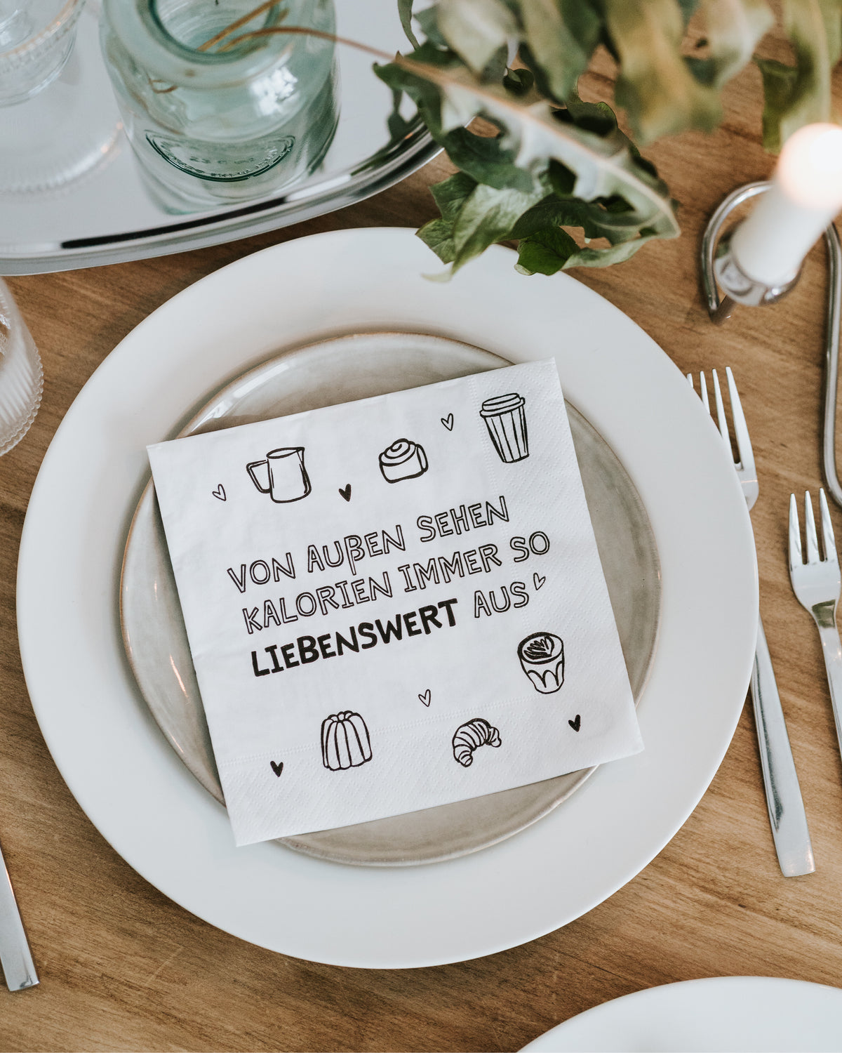 Serviette mit Kalorien-Spruch auf dem Teller, Draufsicht auf die Kaffeetafel – süßes Mitbringsel.
