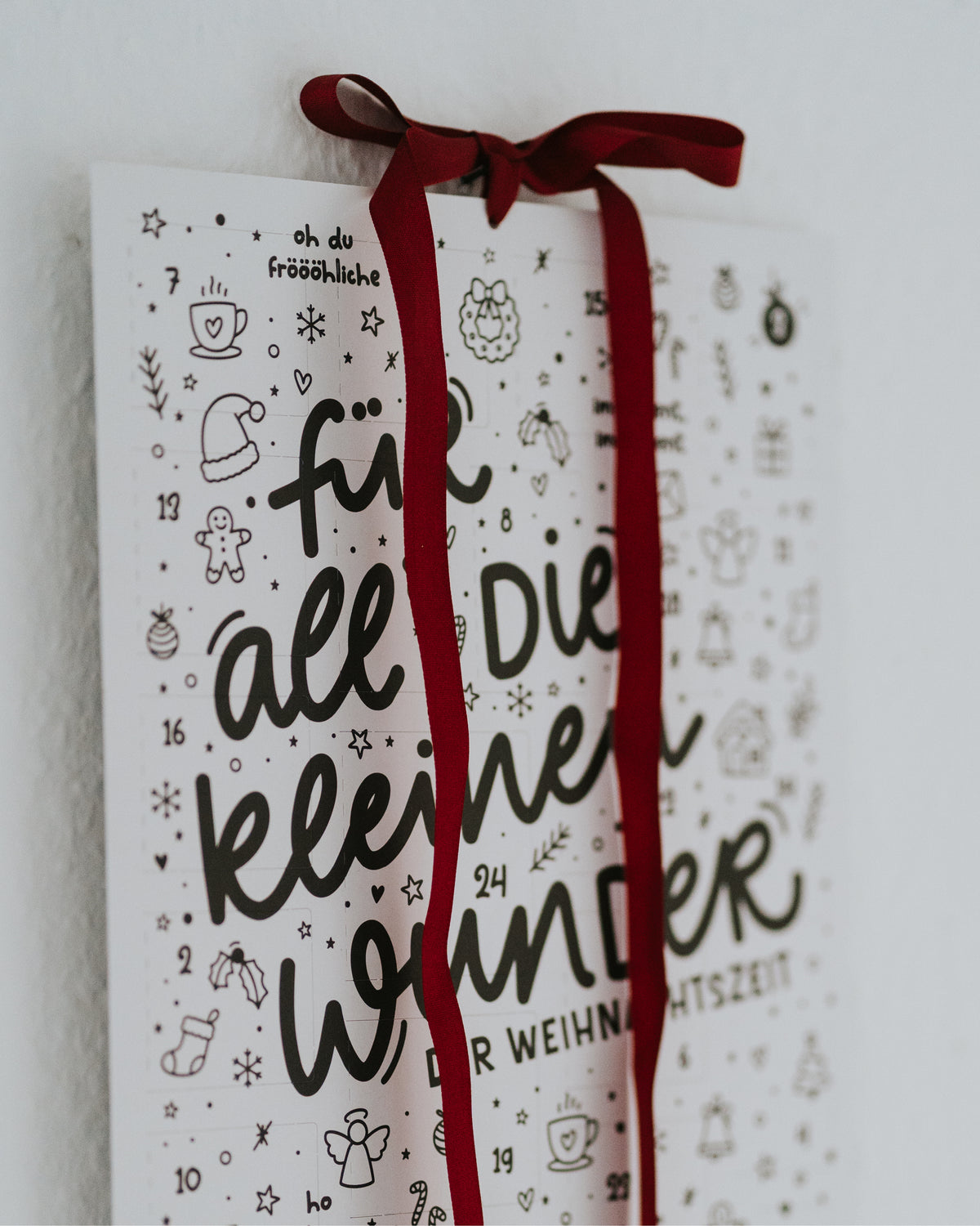 Nahaufnahme des Adventskalenders mit rotem Samtband – Design in elegantem Schwarz-Weiß.
