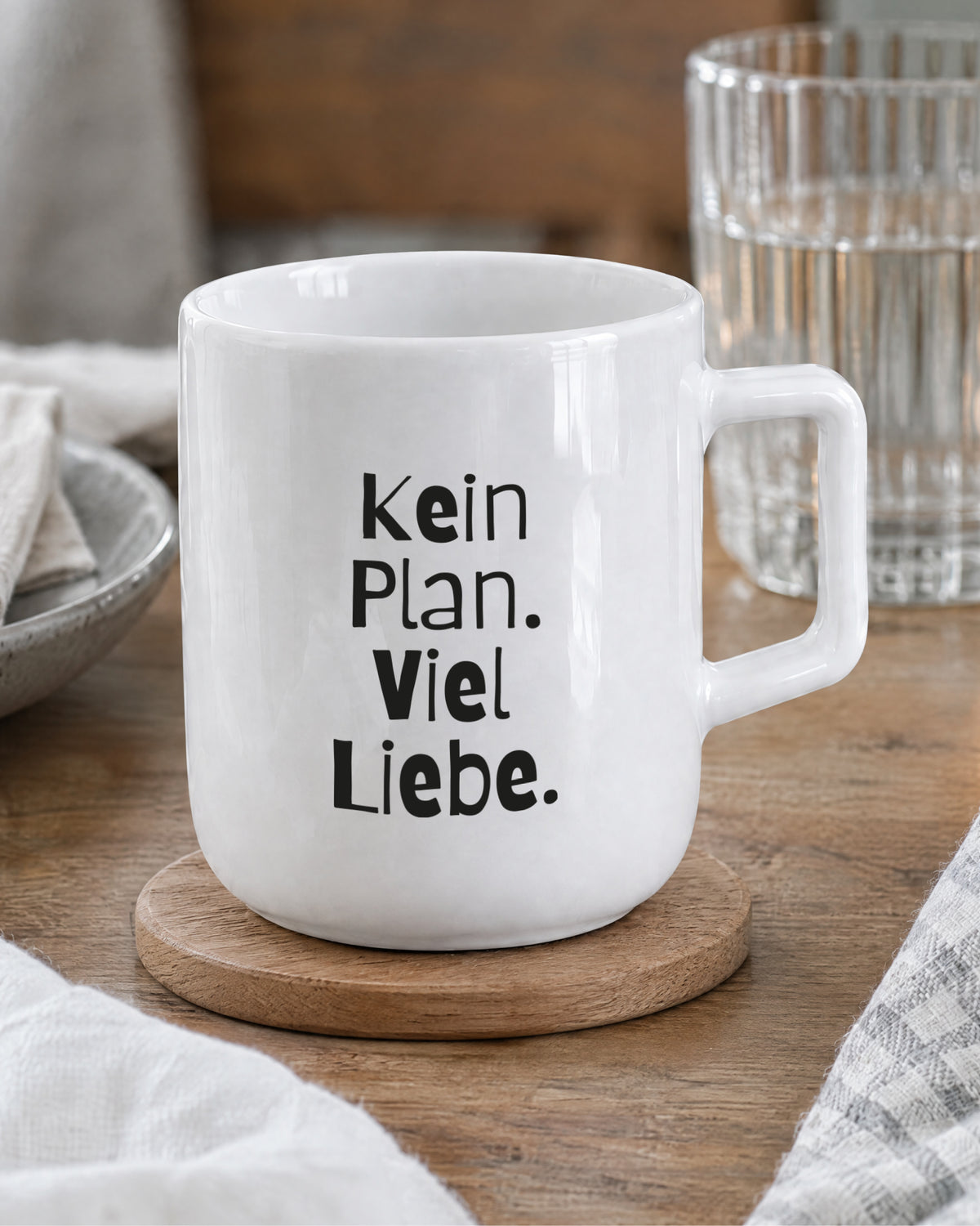 Porzellantasse mit Spruch „Kein Plan. Viel Liebe.“ auf Holzuntersetzer.