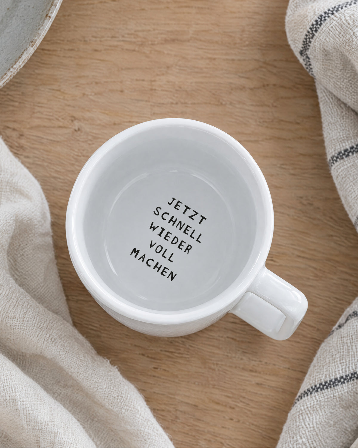 Blick in die Tasse: zweiter Spruch am inneren Trinkrand – „Jetzt schnell wieder voll machen“.