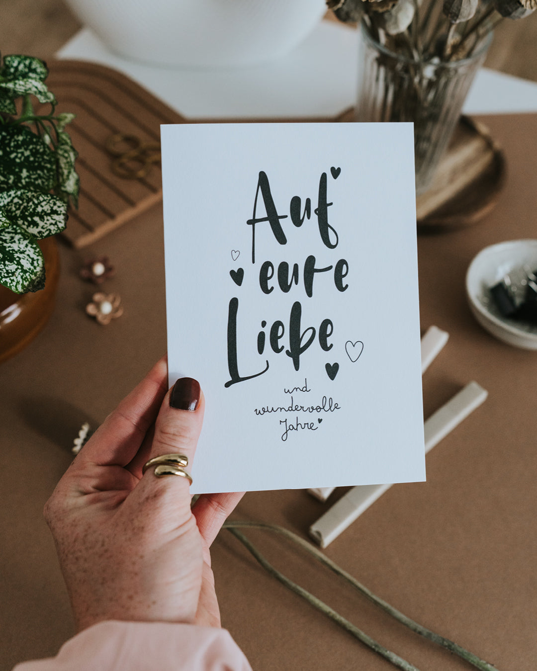 Hand hält Klappkarte „Auf eure Liebe" – hochwertiges Papier im Hochformat mit Herz-Details