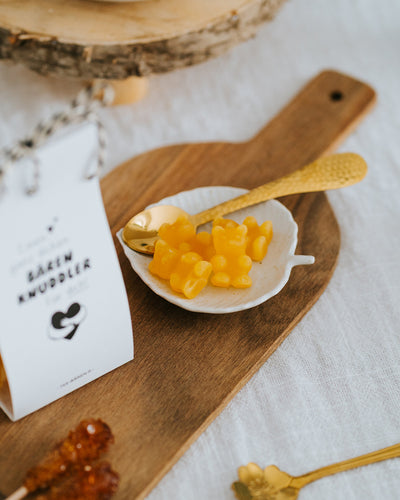 Gelbe Fruchtgummi-Bärchen im Schälchen mit Goldlöffel – als Tee aufgießen oder direkt naschen.