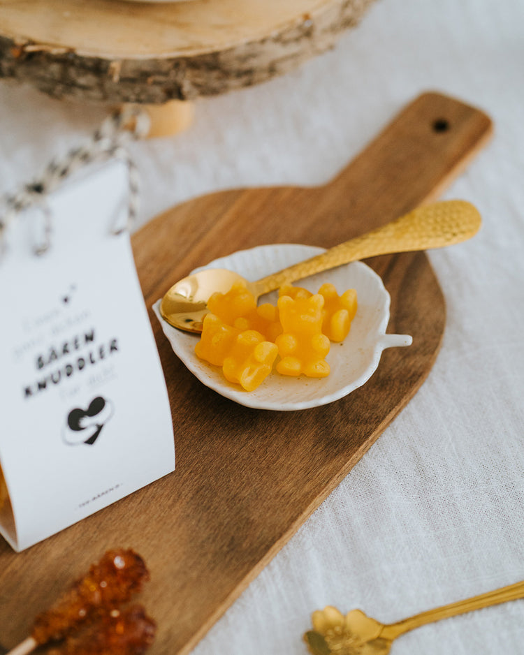 Gelbe Fruchtgummi-Bärchen im Schälchen mit Goldlöffel – als Tee aufgießen oder direkt naschen.