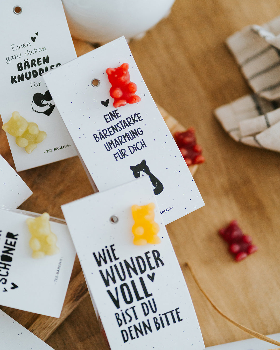 Mehrere Teebären-Motive nebeneinander mit Fruchtgummi-Bärchen – geschenkfertig verpackt.