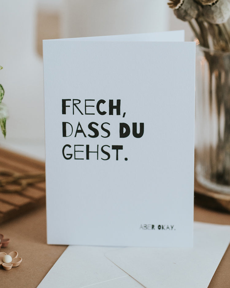 Abschiedskarte „Frech, dass du gehst. Aber okay." aufgestellt mit Umschlag, humorvolles Schwarz-Weiß-Design