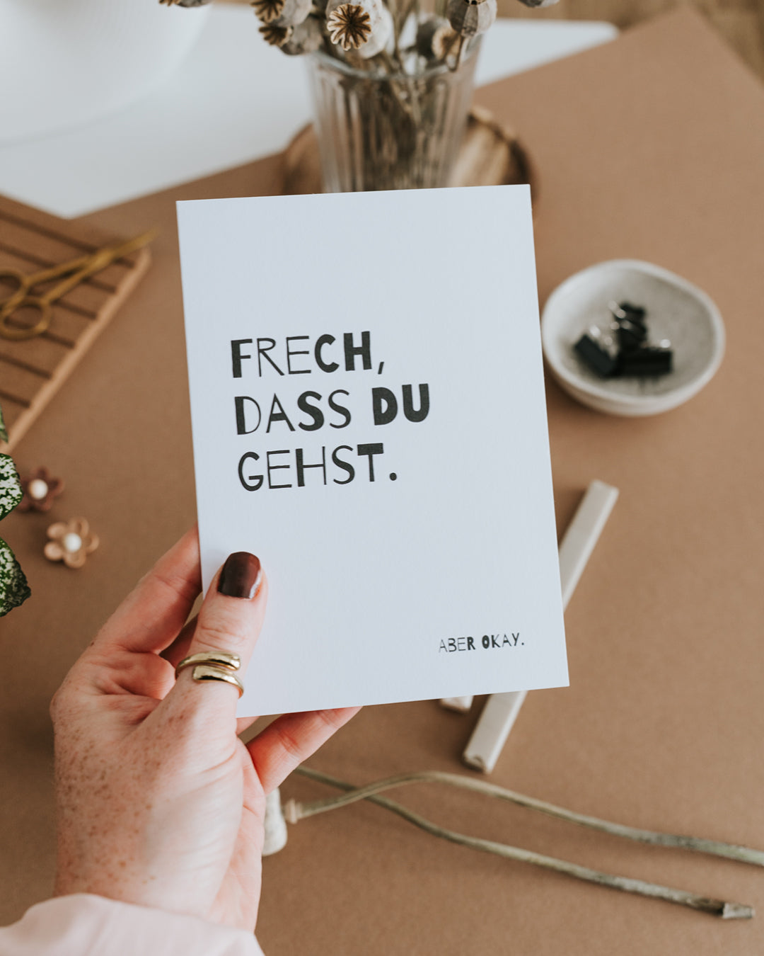 Hand hält Abschiedskarte „Frech, dass du gehst" – hochwertiges Papier im Hochformat