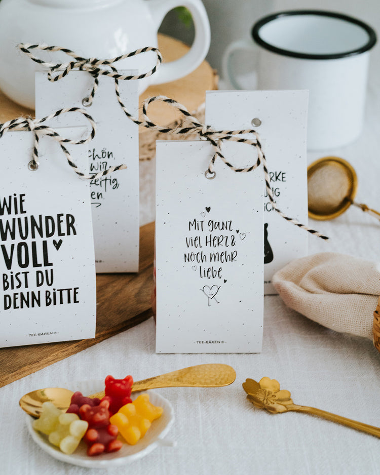 Teebären Mit ganz viel Herz neben weiteren Motiven, Schale mit bunten Bärchen und Goldlöffel.