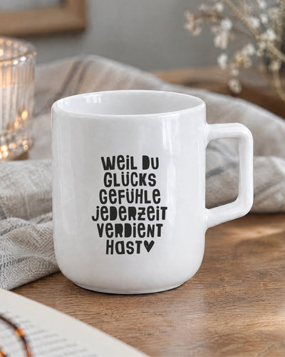 Porzellantasse mit Spruch „Weil du Glücksgefühle jederzeit verdient hast“ und Herz.