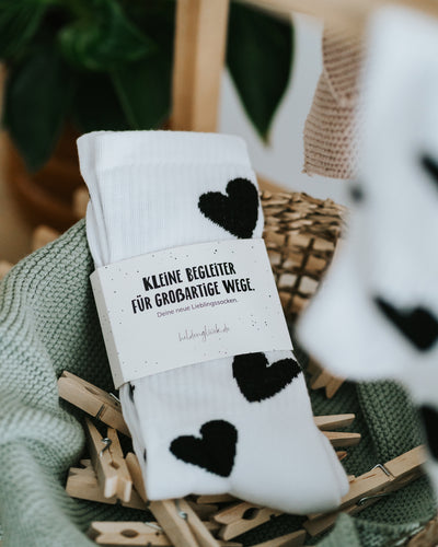 Herz-Socken mit Banderole im Korb – geschenkfertig verpackt.
