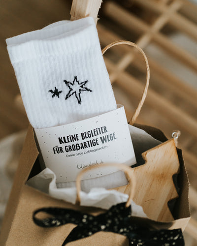 Socken mit Banderole auf Holzleiste – geschenkfertig verpackt.