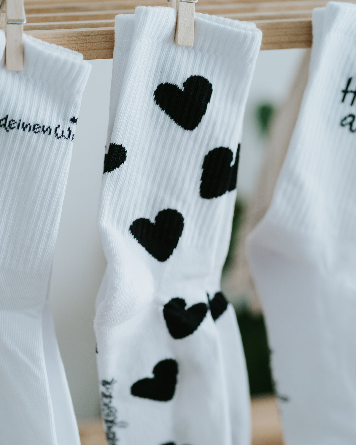 Drei Sockenmotive am Holzregal, Herz-Socken in der Mitte.