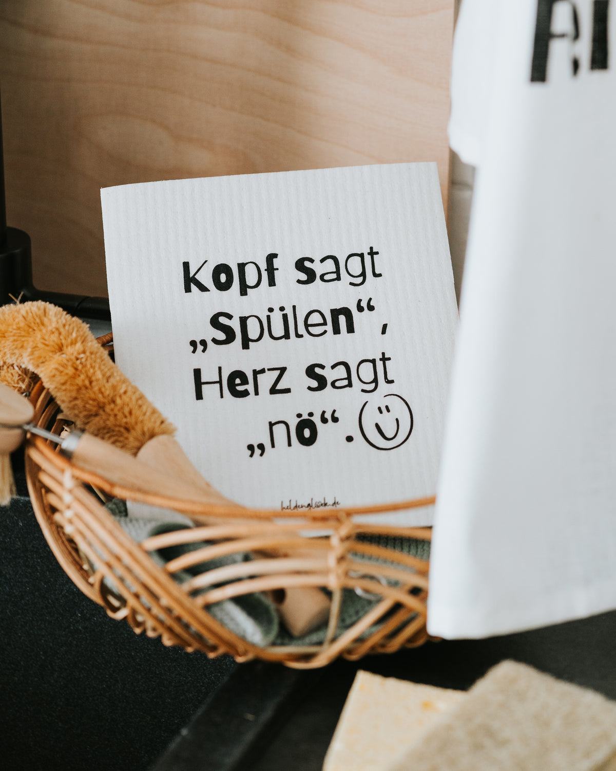 Schwammtuch im Korb, Geschirrtuch daneben – 70 % Cellulose, 30 % Baumwolle.