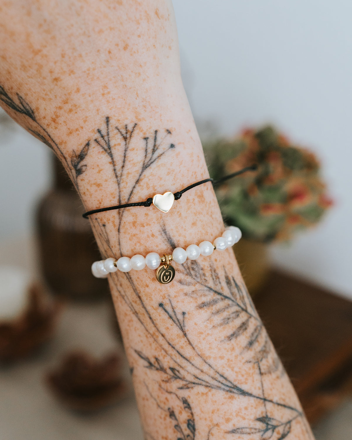Baumwoll-Armband mit goldenem Herz am Handgelenk getragen.