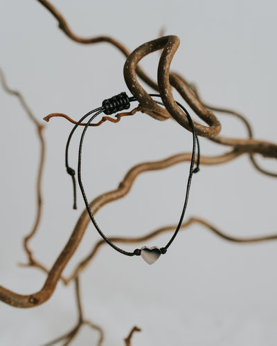 Baumwoll-Armband mit silbernem Herz zwischen Zweigen.