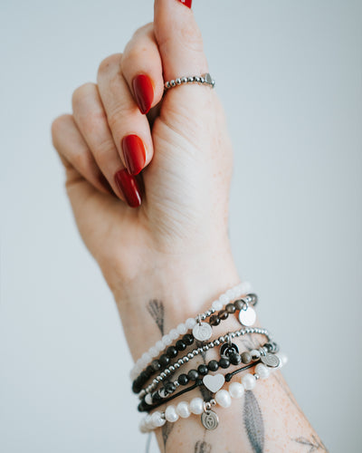 Baumwoll-Armband am Handgelenk, mit weiteren Armbändern kombiniert.