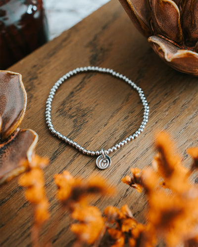 Edelstahl-Armband in Silber auf Holz mit Trockenblumen.