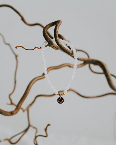 Mondstein-Armband in Gold zwischen Zweigen.