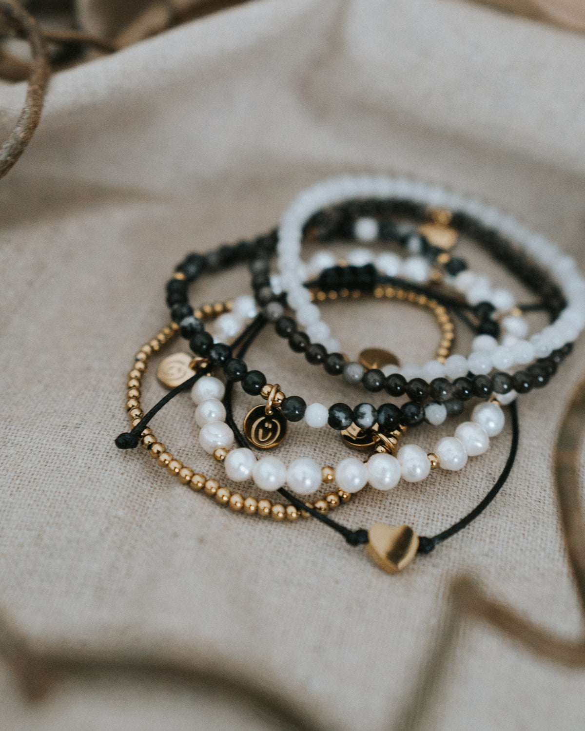 Obsidian-Armband in Gold flach neben Perlen- und Mondstein-Armbändern.