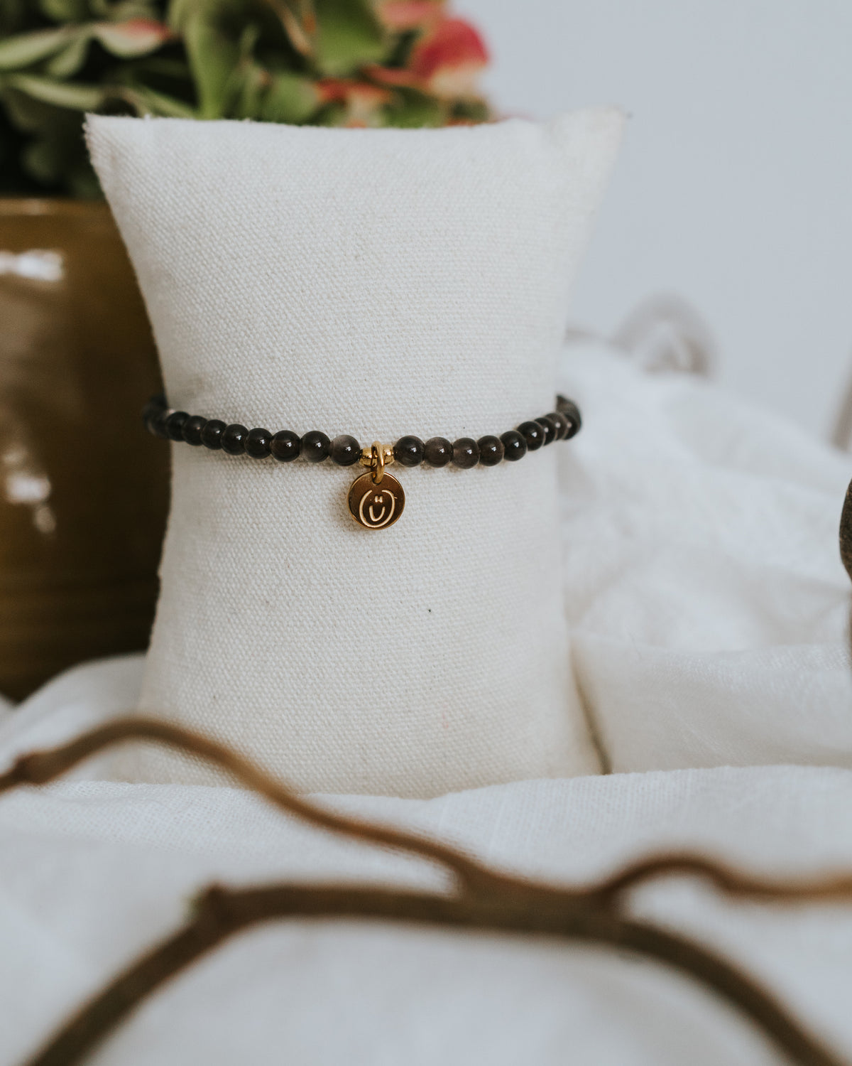 Obsidian-Armband in Gold am Schmuckständer – schwarze Obsidian-Perlen.