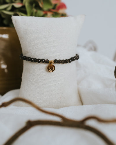 Obsidian-Armband in Gold am Schmuckständer – schwarze Obsidian-Perlen.
