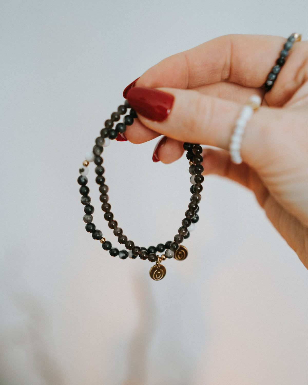 Hand hält Obsidian-Armband in Gold – Größenverhältnis sichtbar.