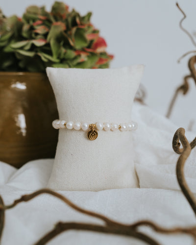 Süßwasserperlen-Armband in Gold am Schmuckständer neben Vase.