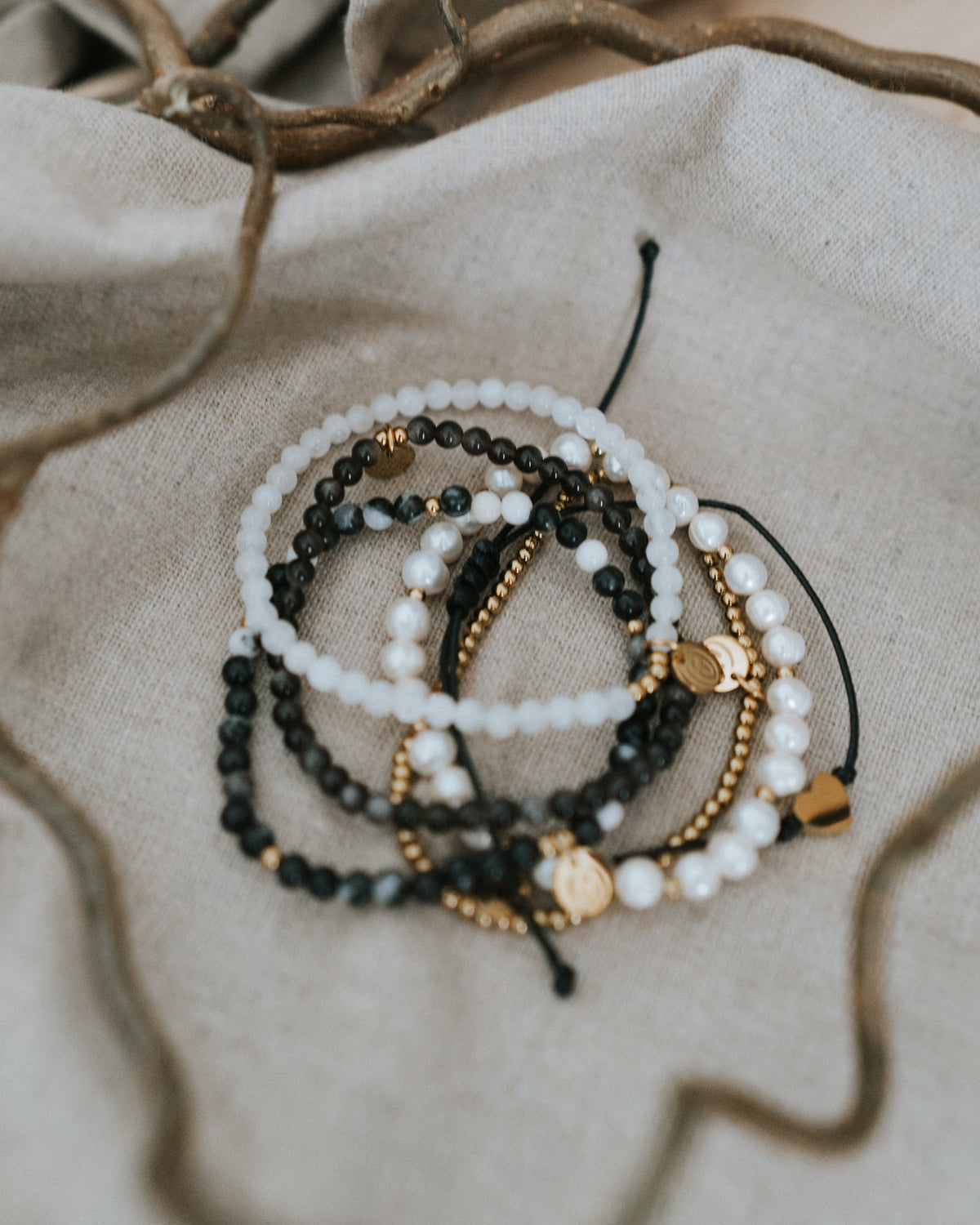 Zebra-Jaspis-Armband in Gold flach auf Leinen, mit Perlen kombiniert.