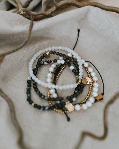 Zebra-Jaspis-Armband in Gold flach auf Leinen, mit Perlen kombiniert.