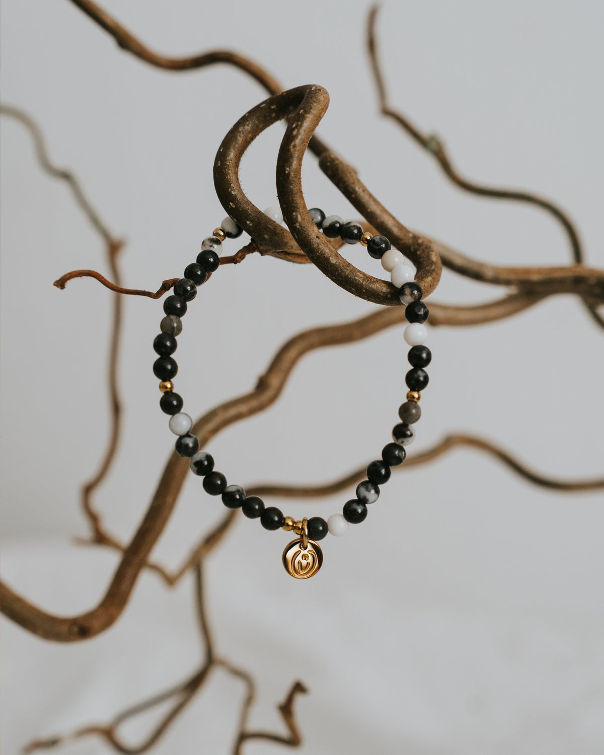 Zebra-Jaspis-Armband in Gold zwischen Zweigen.