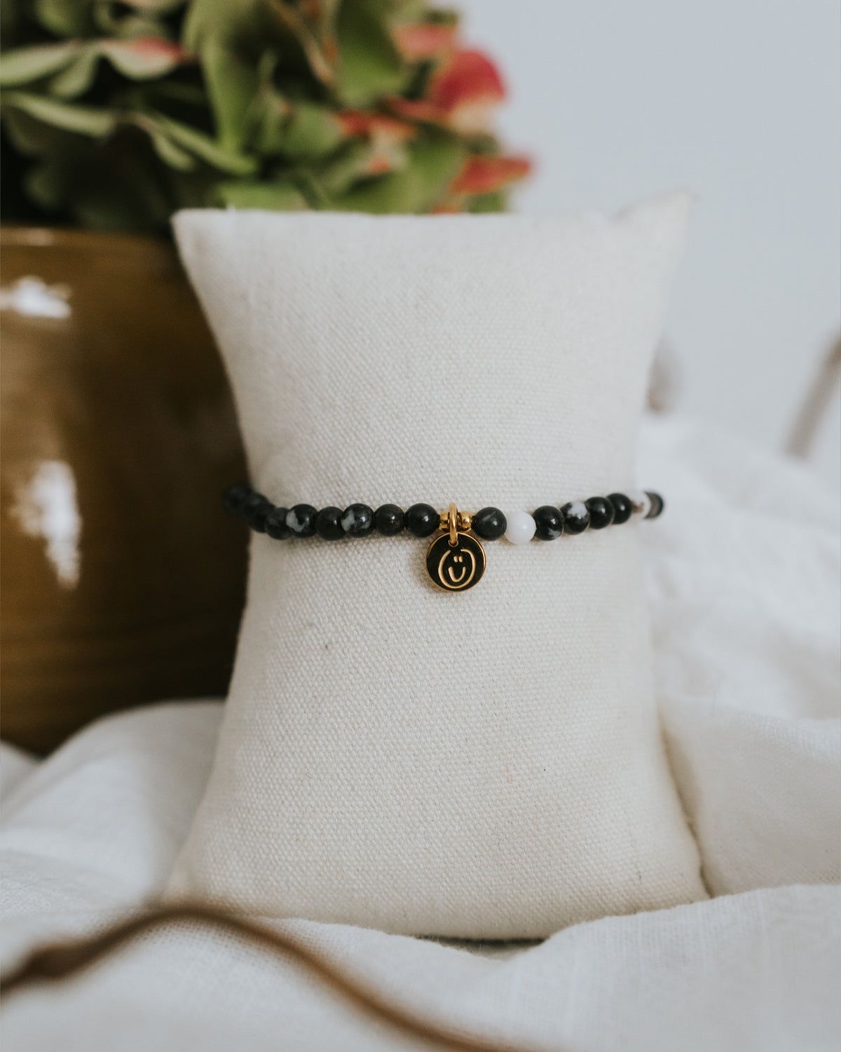 Zebra-Jaspis-Armband in Gold am Schmuckständer mit Trockenblumen.