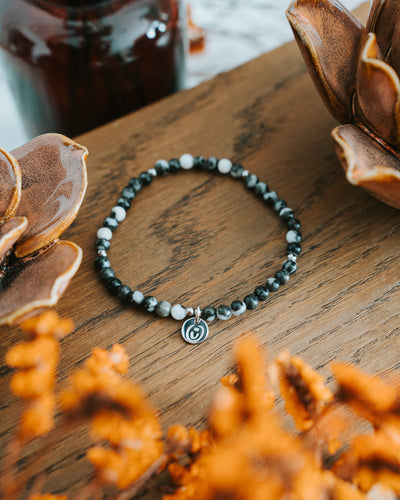 Zebra-Jaspis-Armband in Silber auf Holz mit Trockenblumen.