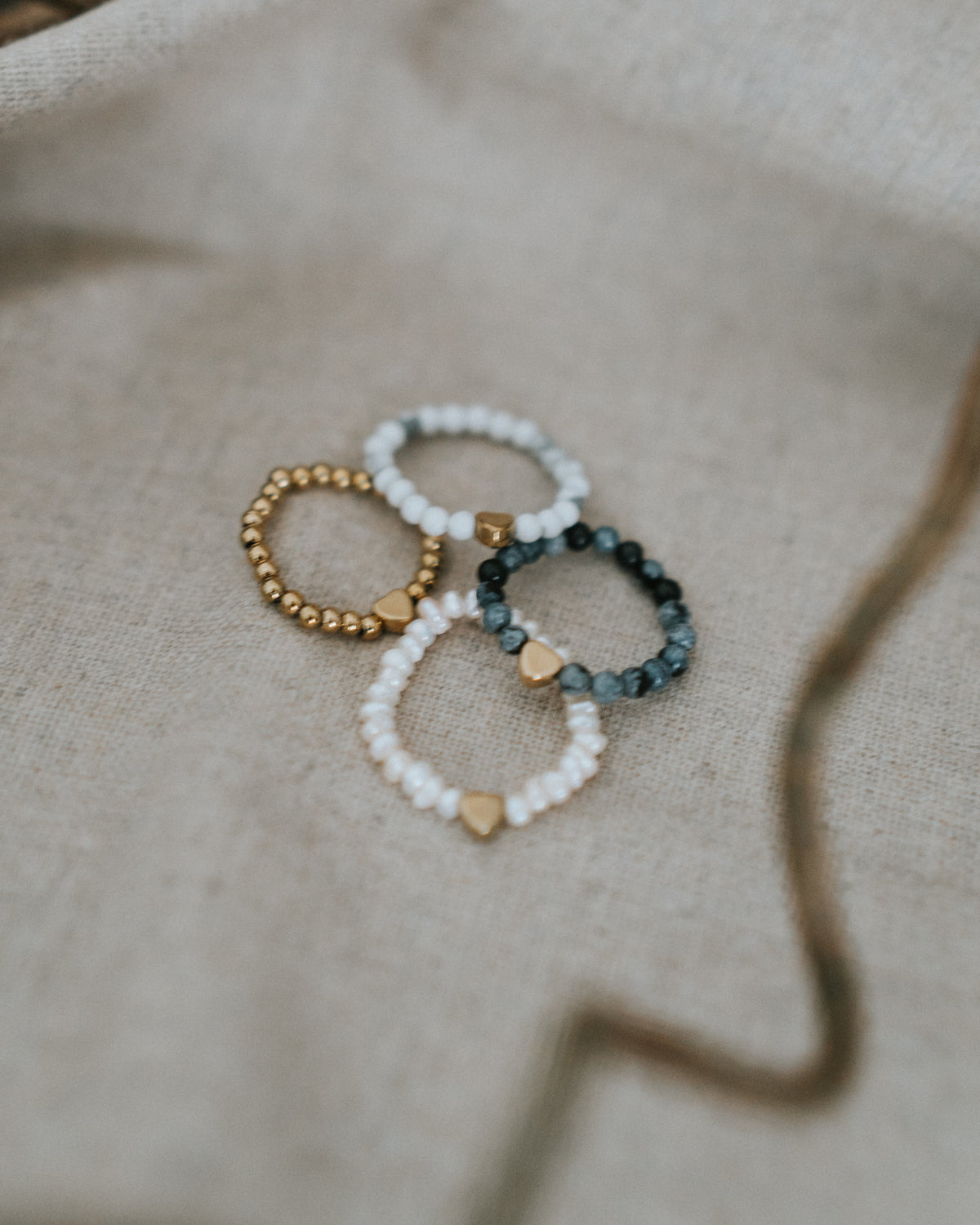 Vier Ringe nebeneinander – Edelstahl in Gold neben Mondstein und Zebra-Jaspis.