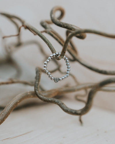 Edelstahl-Ring in Silber an Zweigen – silberne Kugeln mit silbernem Herz.