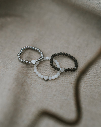 Zwei Ringe auf Leinen – Edelstahl in Silber neben Naturstein-Ring.