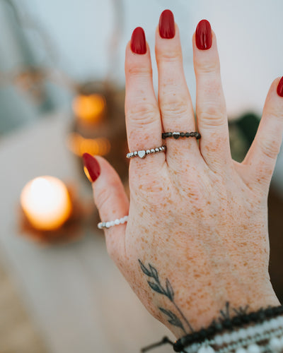 Hand mit mehreren Ringen – Edelstahl-Ring in Silber getragen.