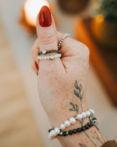 Hand mit Obsidian-Ring und weiteren Ringen.