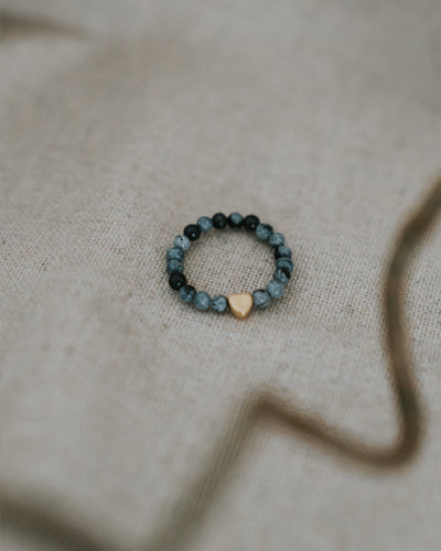 Zebra-Jaspis-Ring flach auf Leinen – Perlen mit goldenem Herz.
