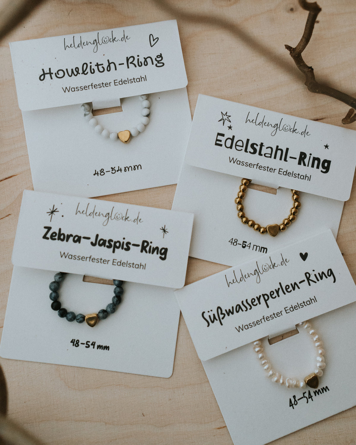 Alle Ring-Varianten mit Karte – Howlith, Edelstahl, Zebra-Jaspis und Süßwasserperlen.