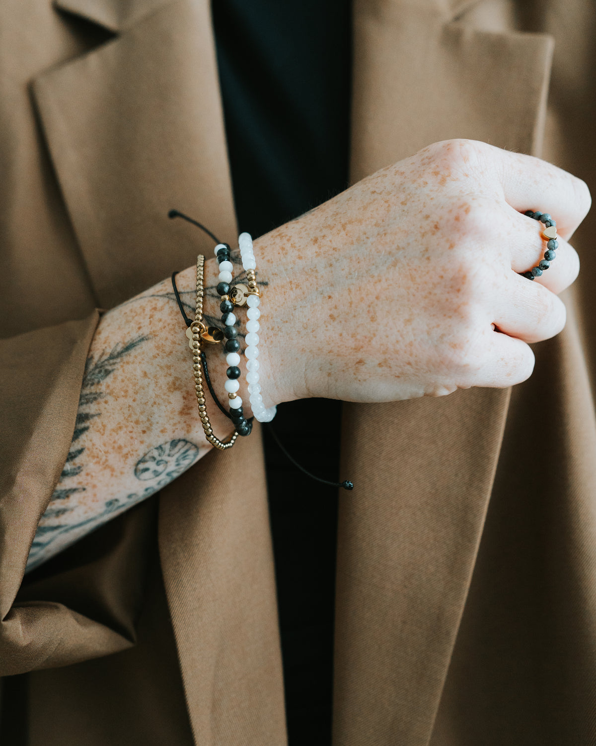 Hand mit Zebra-Jaspis-Ring und Armbändern.