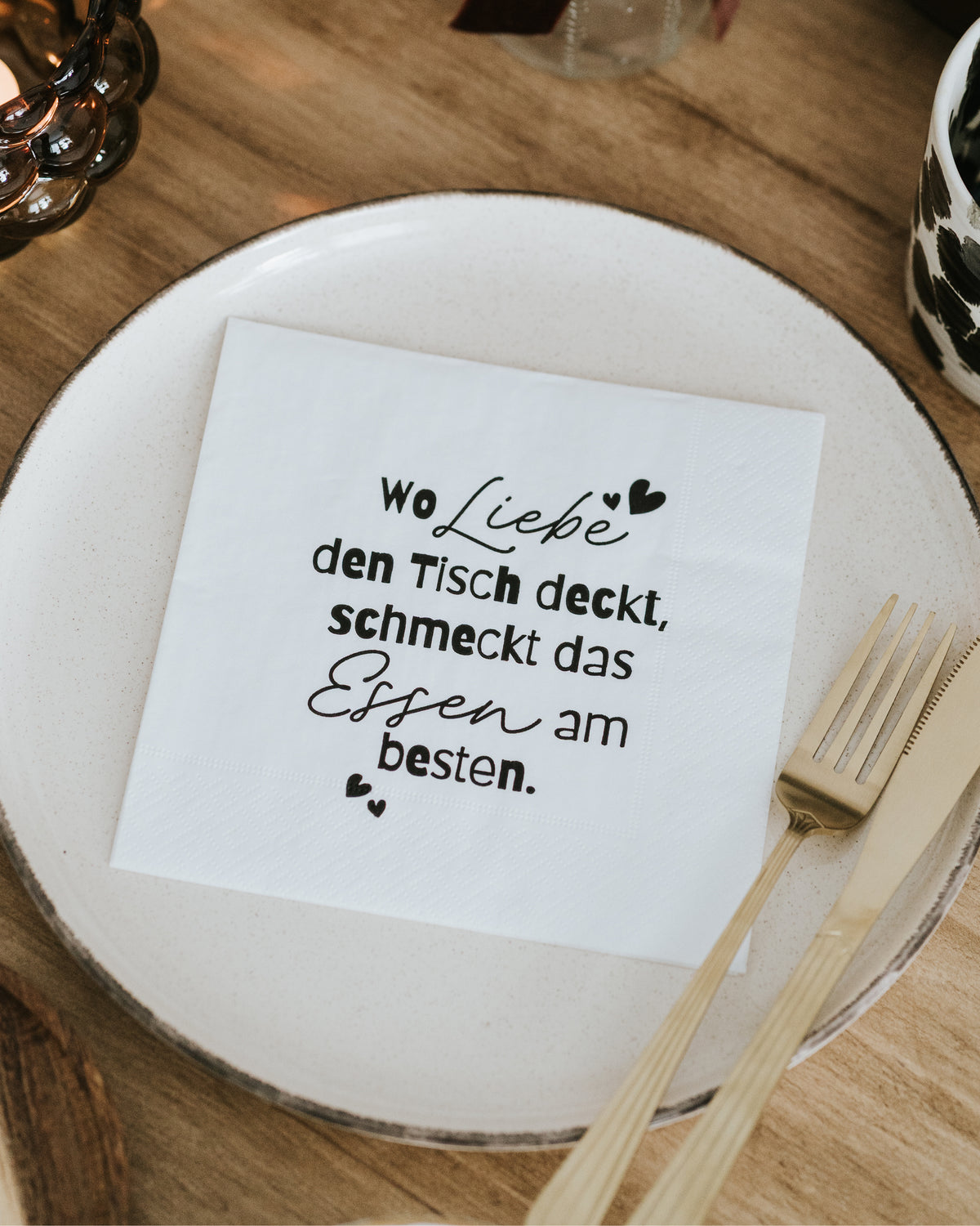 Serviette mit Liebe-Spruch auf dem Teller, Draufsicht mit Holzbesteck – minimalistisches Schwarz-Weiß-Design.