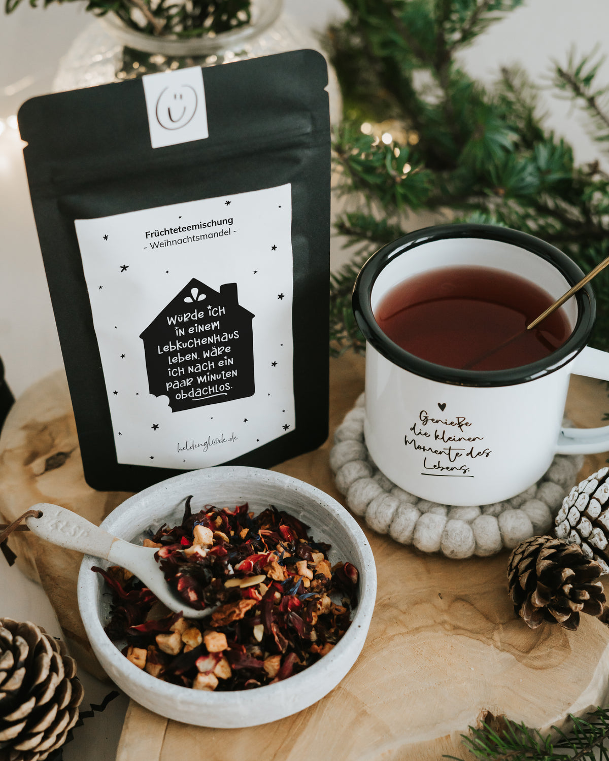 Lebkuchenhaus von Heldenglück, Früchtetee Weihnachtsmandel: Teepackung neben einer Tasse.
